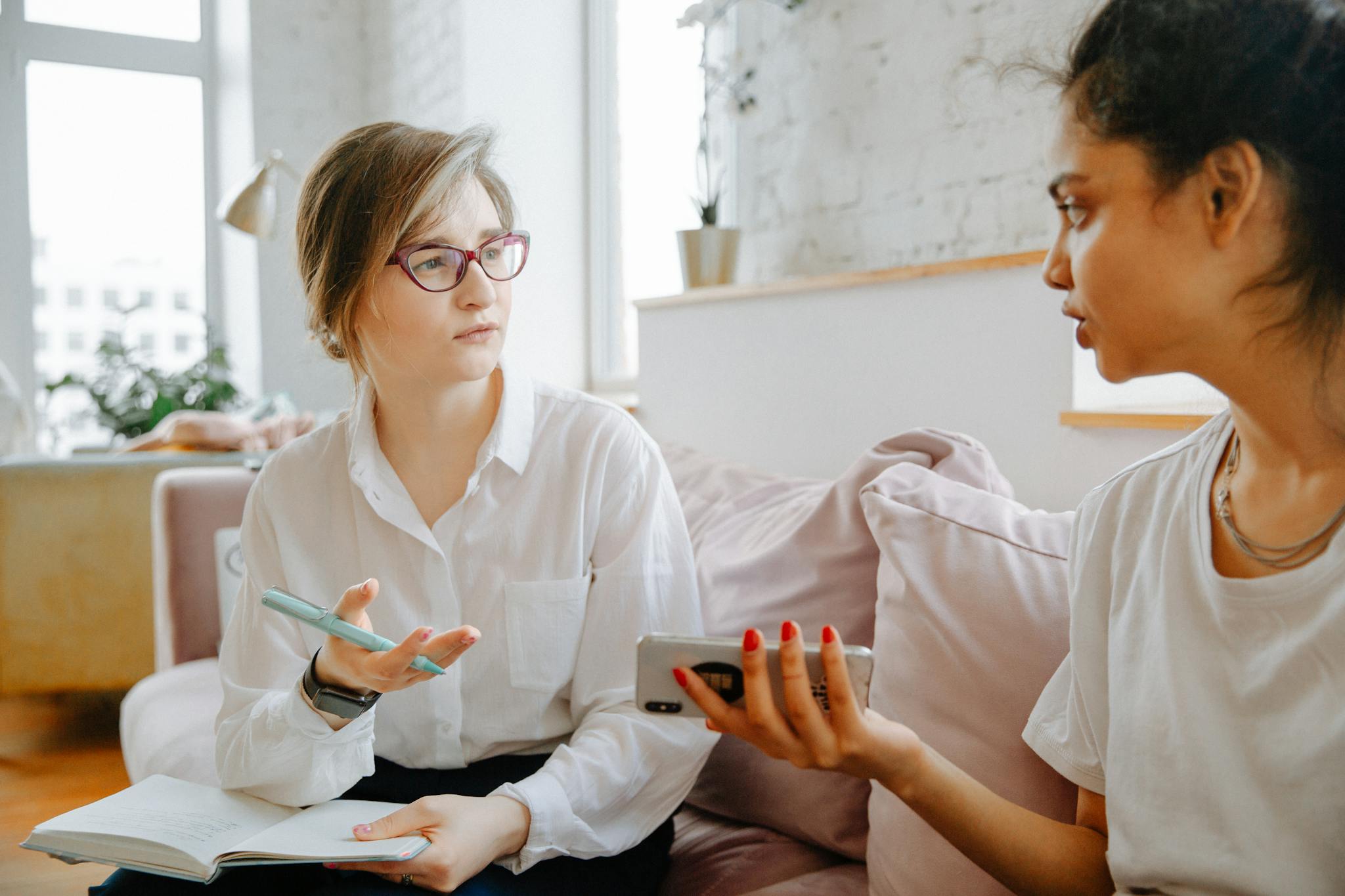 Therapist and client discussing mental health issues during a counseling session in a bright, cozy room.